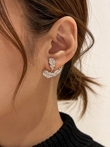 Detailed close-up of zircon-encrusted silver feather earrings with leaf-like design