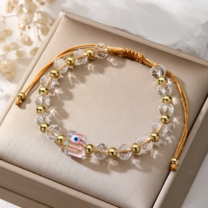 Detail of beaded evil eye bracelet with pink crystal and gold-plated adjustable cord
