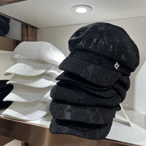 Detailed view of hollow lace newsboy cap with rhinestone buckle on white retail shelf