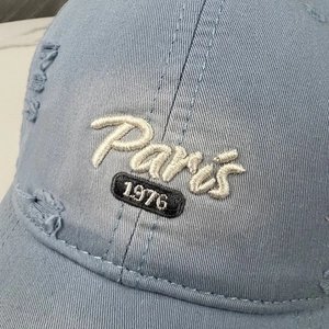Distressed denim baseball cap with white Paris 1976 embroidery and wide curved brim