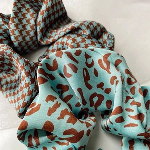 Detailed close-up of blue satin hair scrunchies with leopard and houndstooth patterns