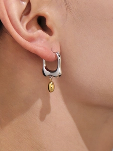 Close-up of minimalist two-tone irregular U-shaped droplet stud earrings on a model ear