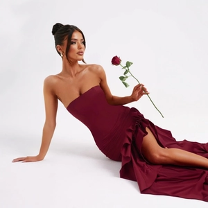 Detail of wine red strapless dress featuring layered ruffles and a high slit design