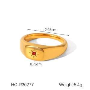 Detail view of gold stainless steel ring with red gemstone and starburst engraving