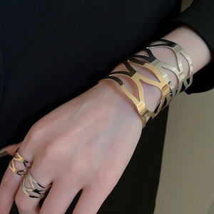 Detail of hollow geometric gold and silver bangle and rings set on a model wrist