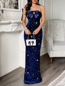 Elegant navy blue sequin off-shoulder evening gown with a large bow and sparkly silver clutch bag