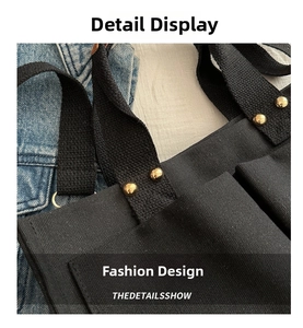 Close-up of black canvas tote bag showing golden rivet details and shoulder strap stitching