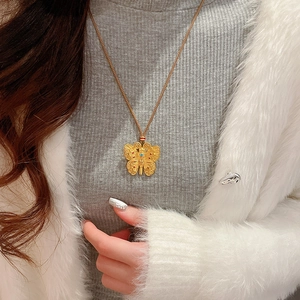 Primo piano della collana con ciondolo a farfalla dorata e dettagli in zircone su modella