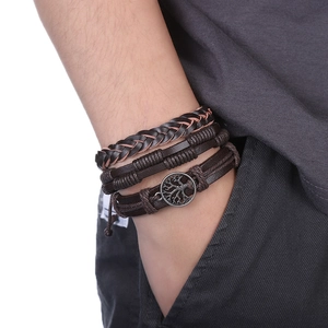 Détail de bracelets en cuir marron multicouches avec pendentif Arbre de Vie et tresses
