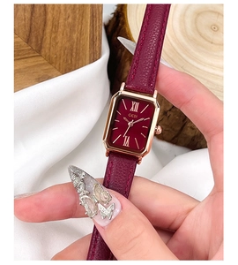 Gros plan d'une montre rectangulaire rouge vin avec boîtier or rose et cuir