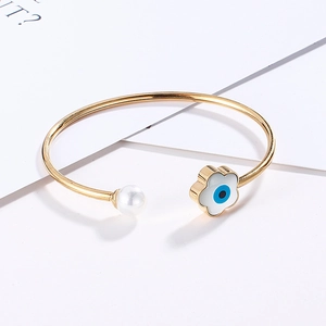 Detailed shot of open bangle with white pearl and blue evil eye enamel charm detail