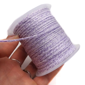 Detail of purple and white braided cord for DIY jewelry making on a clear plastic spool