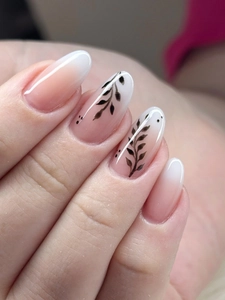Detailed macro view of almond-shaped press-on nails with white gradient and black leaf art