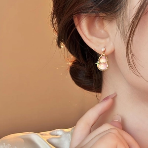 Elegant pink gourd pendant earrings with gold accents and pearl details on model