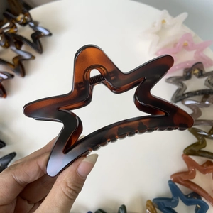 Detail of star-shaped hair claw clip in tortoiseshell finish with a hollow design