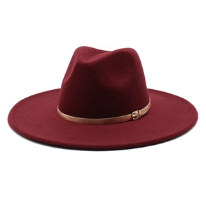 Detail of burgundy wool fedora hat featuring a slim leather band and gold metal buckle
