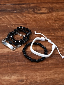 Detail view of four mixed beaded and silver chains with cross charm on wood