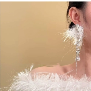 Détail de longues boucles d'oreilles à pompons blancs avec perles et strass brillants