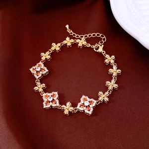 Detail of 18K gold-plated floral bracelet with orange stones on dark silk background