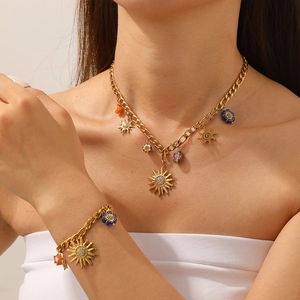 Detailed view of chunky gold NK chain necklace and bracelet with sun and flower charms