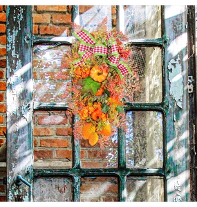 Close-up of autumn wreath with pumpkins and maple leaves on a glass door
