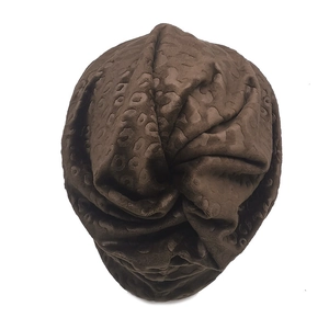 Detailed view of coffee leopard print plush beanie with center knot and soft texture