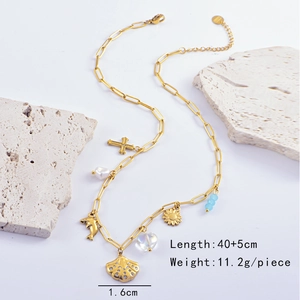 Detail of gold ocean charms including shell, dolphin, and cross on stainless steel chain