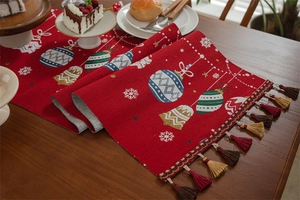 Close-up of red Christmas table runner with festive jacquard patterns and elegant tassels