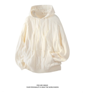 Detail view of the cream-colored cable-knit texture and hooded drawstring on this sweater