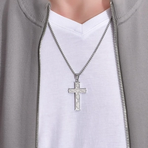 Close-up of a silver Celtic knot cross pendant with etched texture on a steel chain