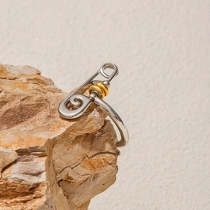 Detailed close-up of a two-tone silver and gold safety pin ring on a natural stone base