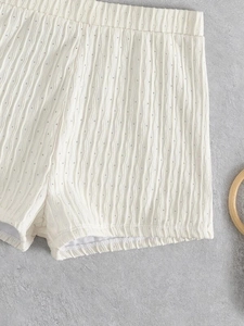 Detail of off-white pointelle knit shorts showing vertical ribbed texture and elastic waist