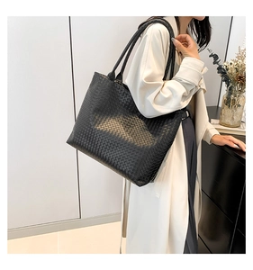 Detailed view of the woven texture and shoulder strap on a black oversized tote bag