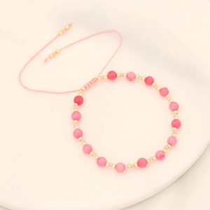 Close-up of pink natural stone beads and golden spacers on adjustable woven bracelet