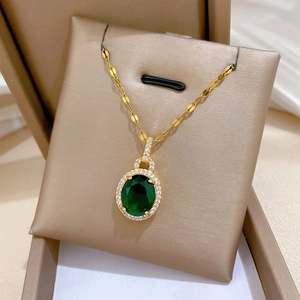Détail macro du pendentif doré avec pierre vert émeraude et halo de zircons brillants