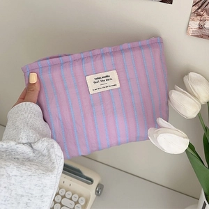 Portable purple striped canvas toiletry bag with zipper closure and woven label