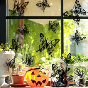 Black 3D skull butterfly wall decals on a window with Halloween pumpkins and green plants