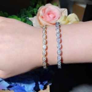 Elegant gold and silver tennis bracelets with oval-cut zircons worn on the wrist