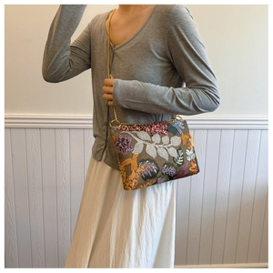 Detail of brown sequin embroidery evening clutch bag with golden chain strap on model