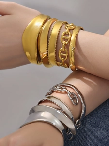 Detalle de brazaletes minimalistas de acero inoxidable pulido en acabado oro y plata