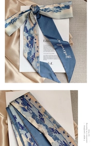 Close-up of silk scarf with blue landscape art print and 'be yourself' text detail