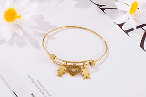 Detail of adjustable gold titanium steel bangle with heart, girl, and bear charms