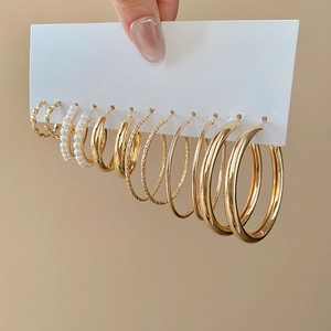 Detail von 9-teiligem goldenem Ohrring-Set mit Perlen und Creolen auf Displaykarte