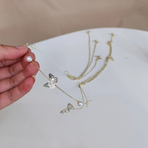 Detail of a gold metal headband featuring zircon butterflies and elegant pearl tassels
