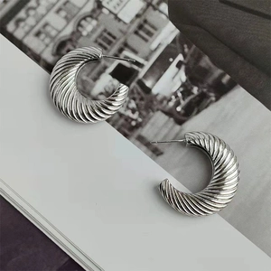 Close-up of silver-tone hoop earrings featuring a textured spiral design on a trendy background
