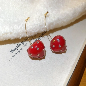 Macro shot of red cherry resin earrings with sparkling rhinestones and gold hooks