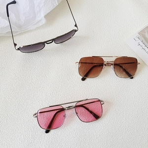 Flat lay of retro square double-bridge kids sunglasses in grey, brown, and pink metal frames