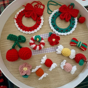 Detailed set of Christmas crochet ornaments with cherry and bow motifs on wooden tray