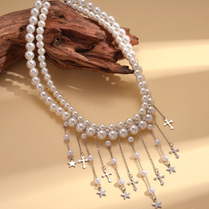 Détail d'un collier de perles double épaisseur avec breloques étoile et croix sur bois