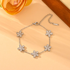 Bracelet en acier inoxydable argenté avec cinq breloques fleurs et détails blancs